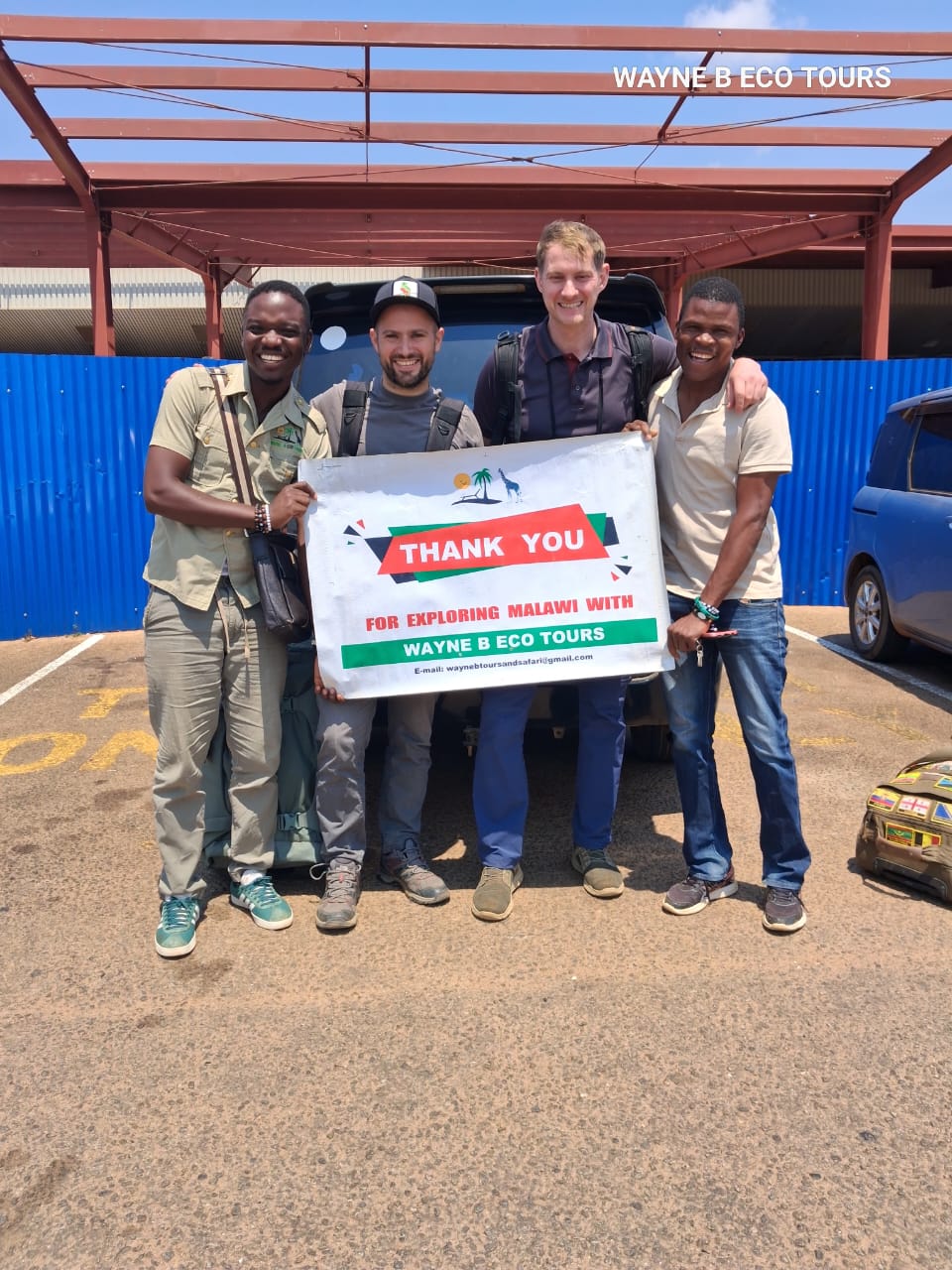 Guests and guides holding a thank-you banner at the airport after a tour