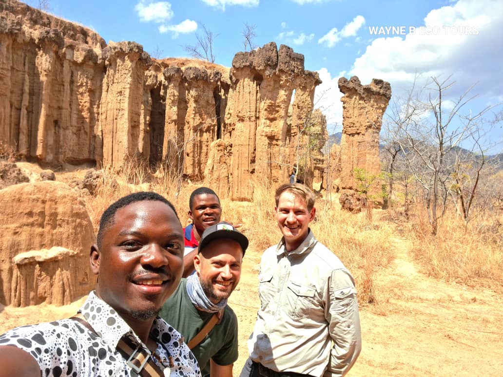 Guides and guests taking a selfie before eroded sandstone canyons
