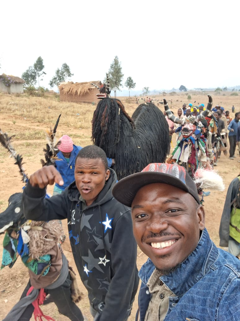 Selfie with a Nyau dancer procession moving through the village