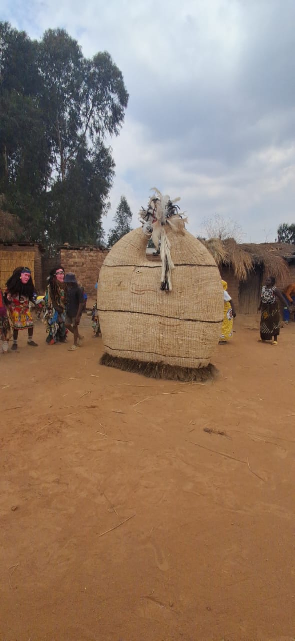 Large woven zebra-striped Gule Wamkulu structure dancing in a village clearing