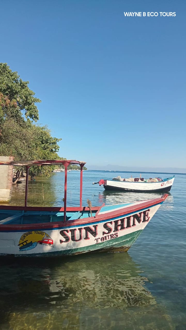 Sun Shine Tours boat moored in the clear shallows of Lake Malawi