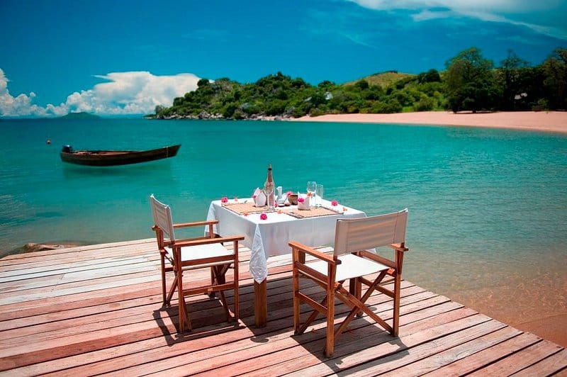 Private table set for two on a jetty above turquoise Lake Malawi