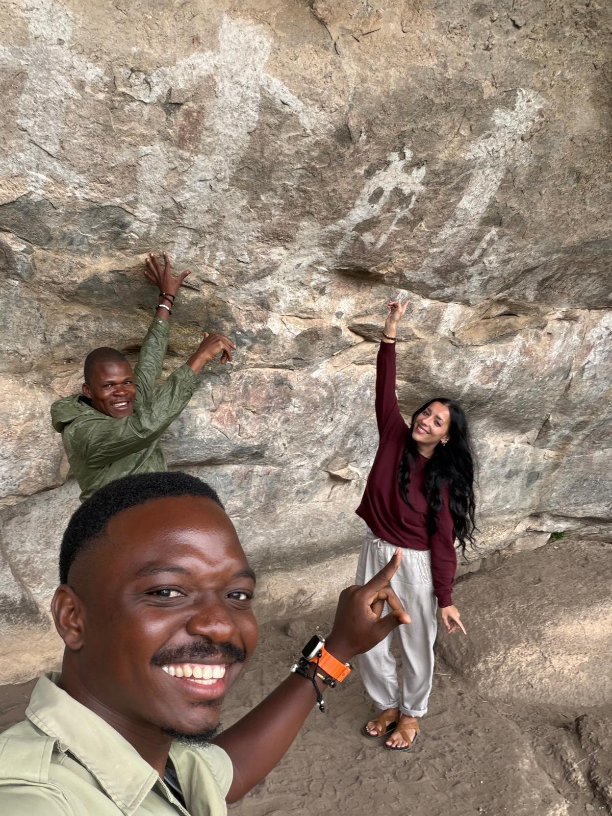 Guide and guests pointing at white rock paintings in a shelter